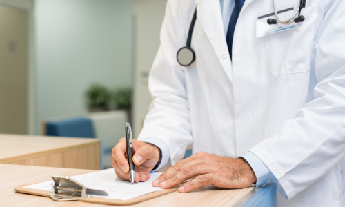 Lekarz w białym fartuchu ze stetoskopem wypełniający dokumentację medyczną w klinice, podkreślający profesjonalizm w badaniach klinicznych.
